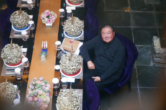 在上海黔香阁,"掌门人"李建忠把纯银苗族头冠和高脚杯,中西餐具一起摆