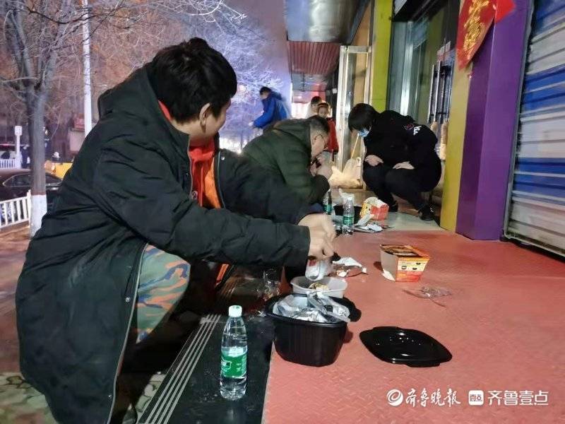 冬夜飘雪，泰安自来水公司抢修人员在路边匆匆解决晚饭