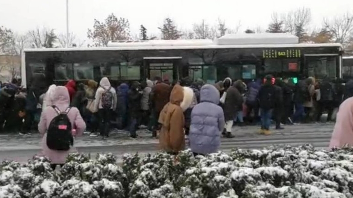 道路结冰难行，青岛百人风雪中共推公交车爬坡