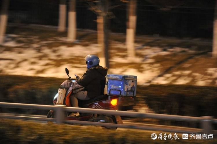 寒潮来袭的深夜街头,外卖小哥匆匆忙忙赶路