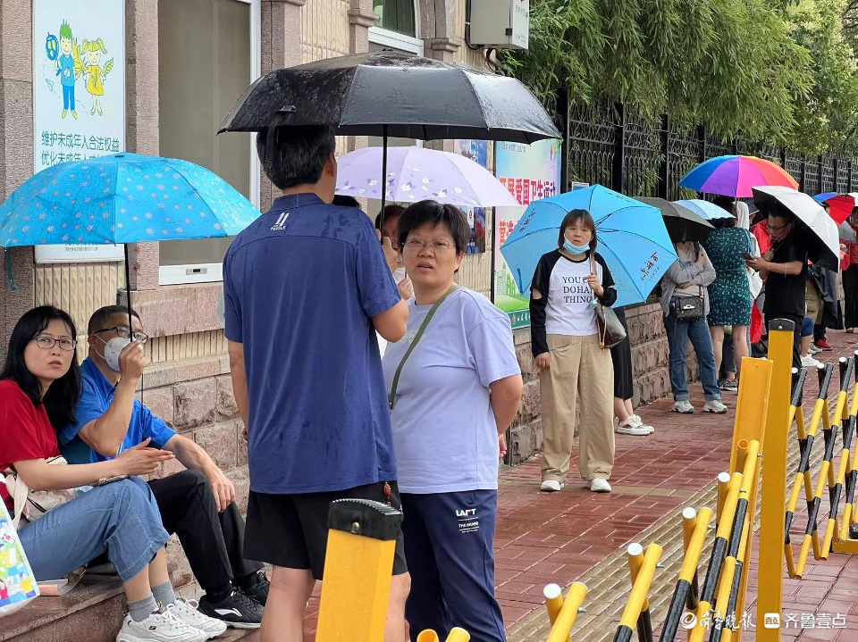 开考后家长不舍离去，屋檐下避雨冷风中候场
