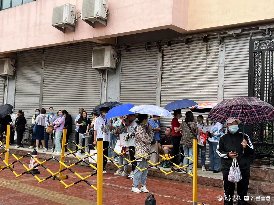 开考后家长不舍离去，屋檐下避雨冷风中候场