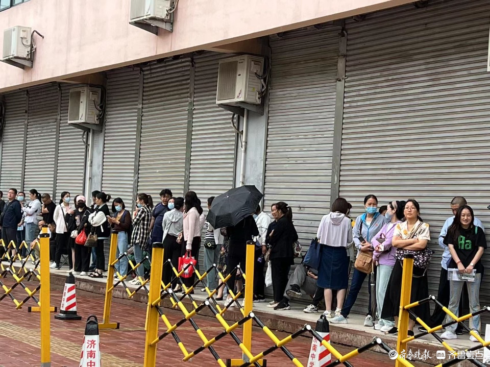 开考后家长不舍离去，屋檐下避雨冷风中候场