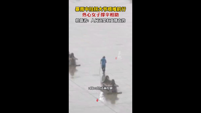 暴雨中拄拐大爷艰难前行，热心女子撑伞相助，拍摄者：人间真情在