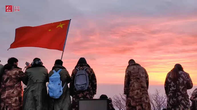 五四青年节的泰山之巅，青年人高举五星红旗迎日出