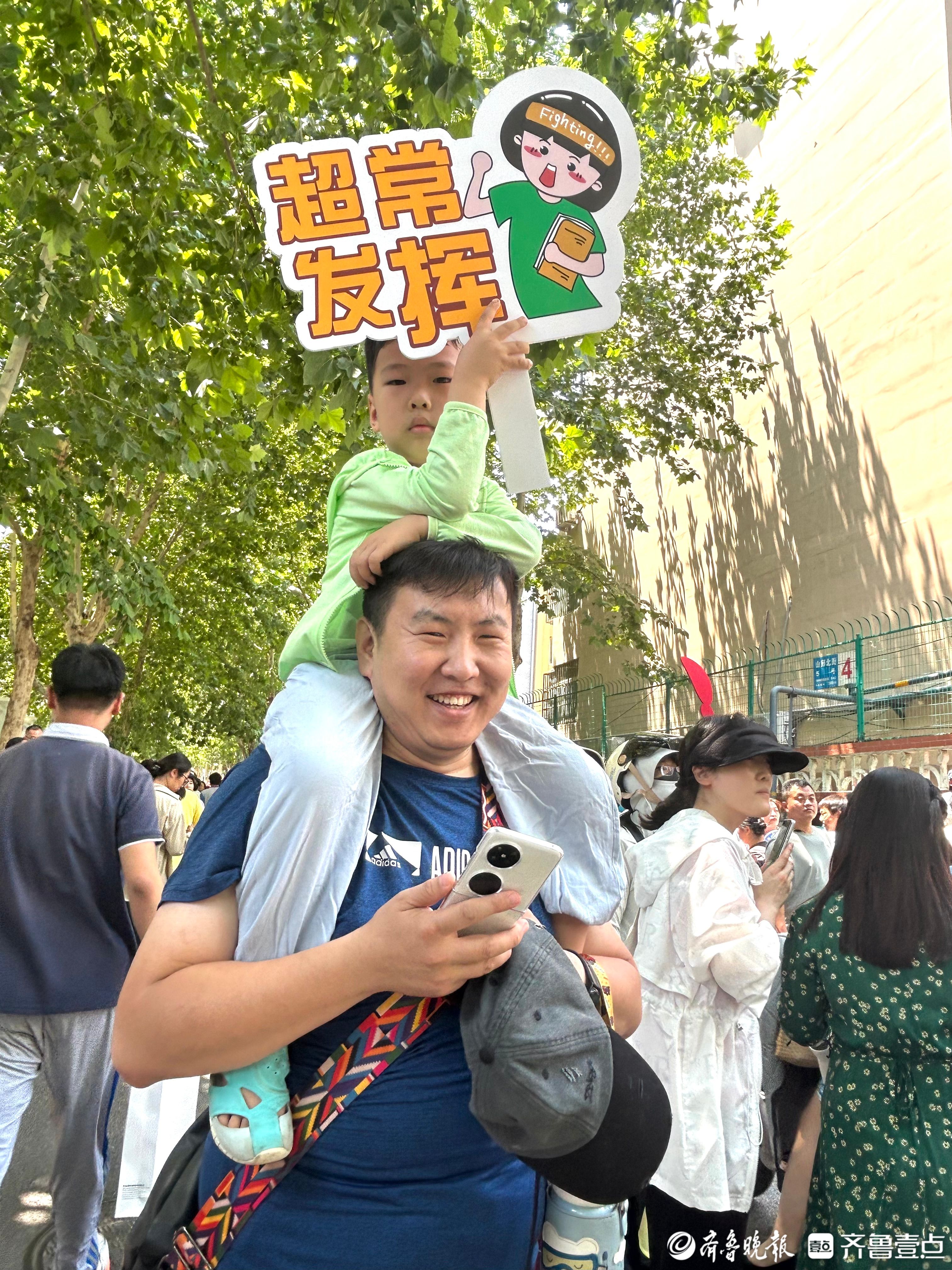 5岁小朋友骑上爸爸肩头迎接姐姐出考场