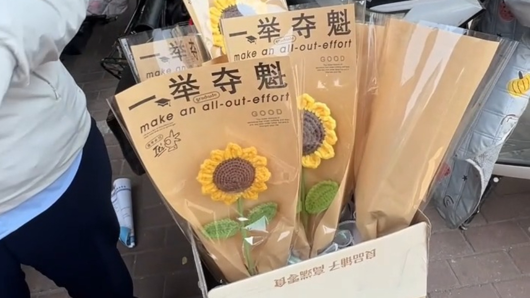 果然视频丨泰安中考迎胜中学考点，女子摆摊卖手工向日葵，路人经过称贵