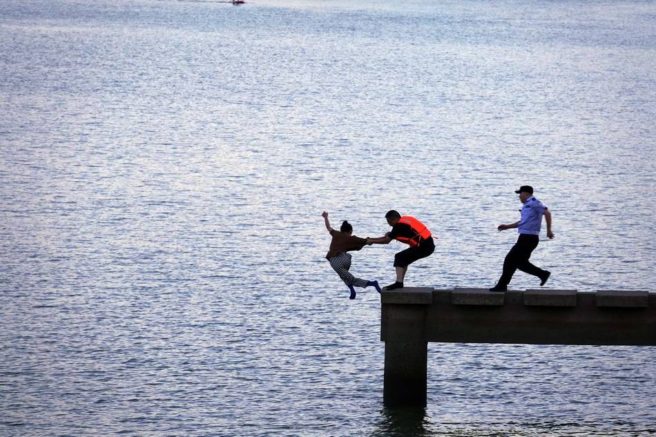 江游览桥的江边观景台上,两名民警正快速拉住一名欲投江寻短见的女子