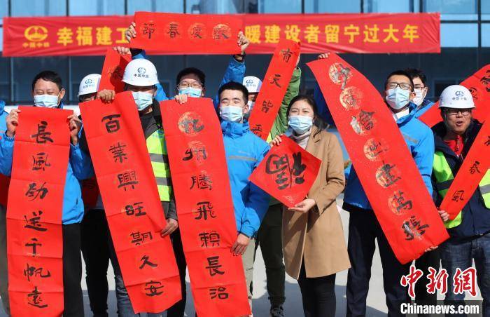 中铁建工项目部就地过年的建设者手拿"福"字和春联拍摄大合影.