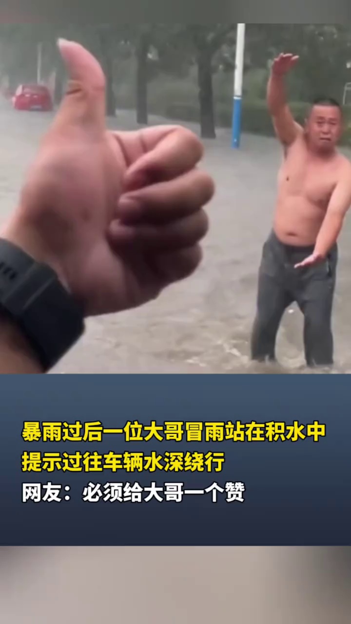 暴雨过后一位大哥冒雨站在积水中，提示过往车辆水深绕行