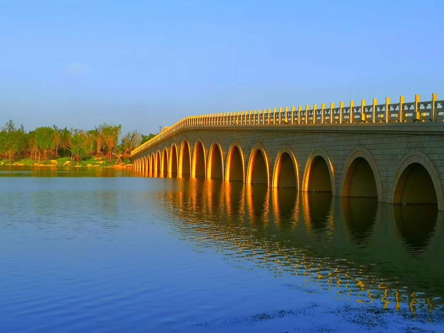 碧水蓝天夕阳照金光穿孔烟雨桥