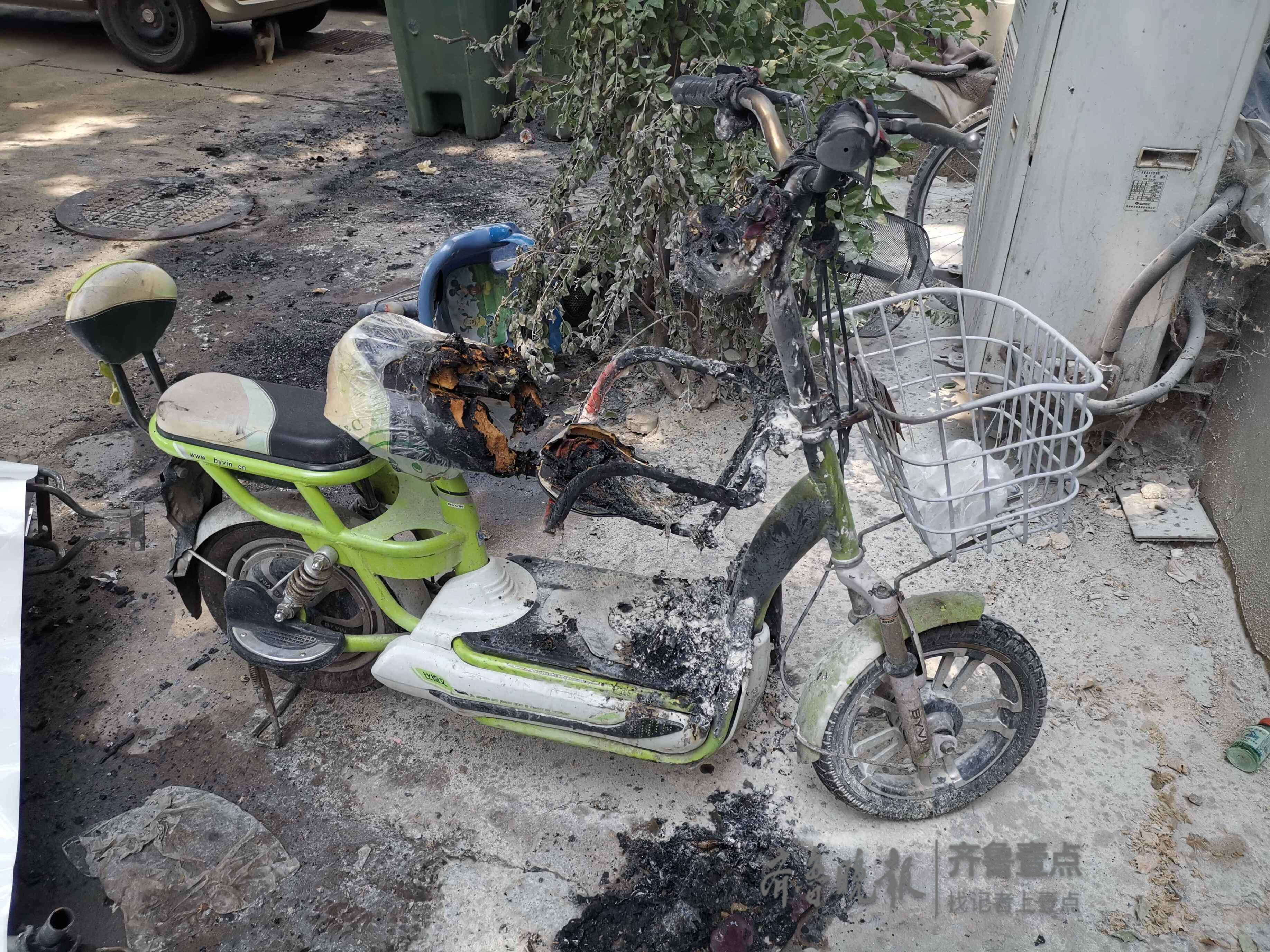 事发居民楼下一片狼藉,多辆电动车被烧毁只剩下铁架,被白色的布覆盖着