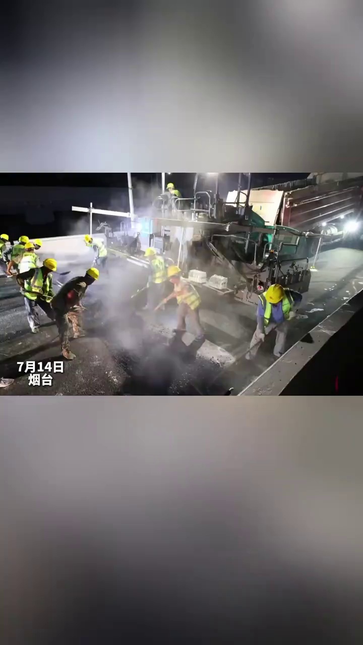 7月14日晚，港城西大街互通立交上，工作人员在对桥面进行沥青铺装。目前，施工单位采取现场24小时不间断施工，力争9月底前实现立交整体完工通车，据了解，该立交建成后将是烟台市最大三层互通立交。